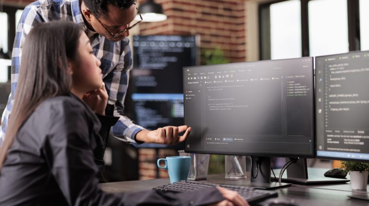 Diverse programmers discussing about html code Diverse programmers discussing about html code compiling discovers errors, standing in front of multiple screens in startup office. Software developers working on server interface development.