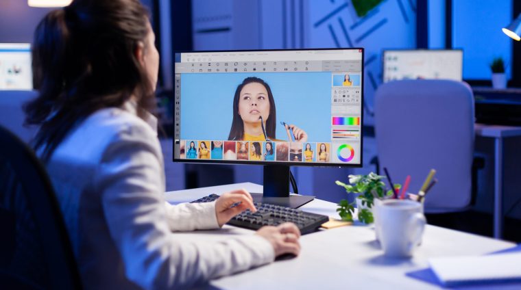 Creative creator doing portrait retouch using color grade Creative creator doing portrait retouch using color grade late at night in professional editing office. Graphic editor retouching photos of a client on performance pc before deadline